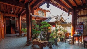 A traditional wooden building with a courtyard, featuring potted plants and a wooden table. - Songhe Boutique Hostel (Lijiang)