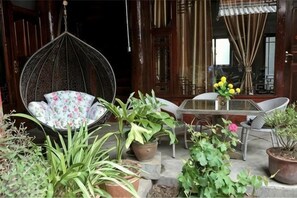 A hanging chair, a table with chairs, and potted plants in a courtyard.