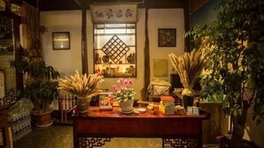 A traditional Japanese interior with a wooden table, potted plants, and a decorative window. - Songhe Boutique Hostel (Lijiang)