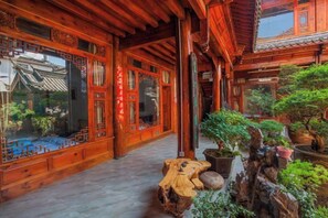 A traditional wooden corridor with intricate door designs and a stone pathway. - Songhe Boutique Hostel (Lijiang)