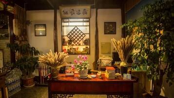 A traditional interior with a wooden table, potted plants, and a decorative screen.