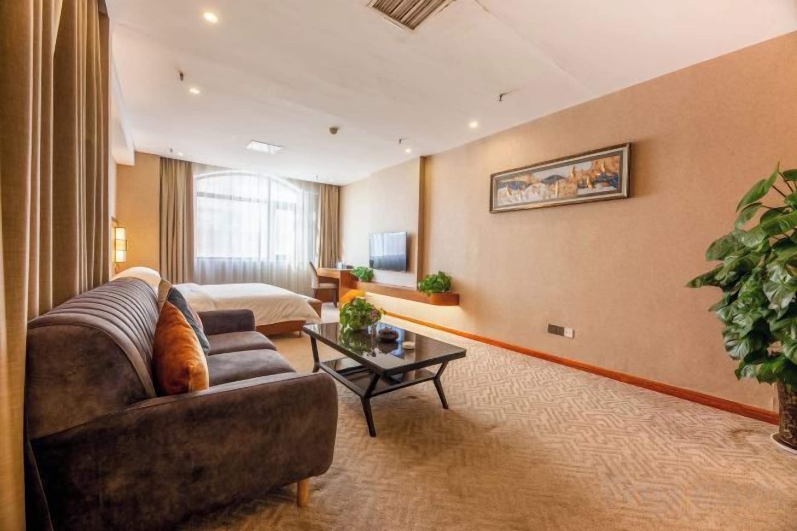 A hotel room with a bed, a sofa, a coffee table, and a television.