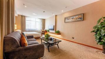 A hotel room with a bed, a sofa, a coffee table, and a television.