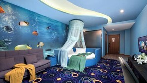 Una habitación con un mural azul de peces, una cama con dosel, un sofá y una alfombra estampada.