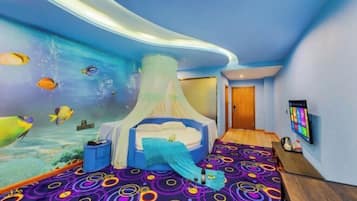 A bedroom with a bed, a TV, and a mural of fish on the wall.