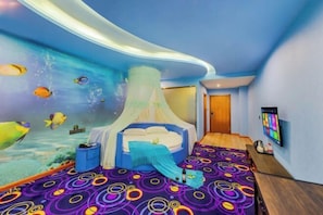 Een slaapkamer met een bed, een televisie en een muurschildering van vissen.