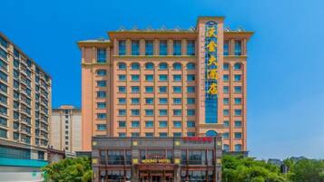 A multi-story hotel with a prominent entrance, a large sign above the entrance, and a clear sky.