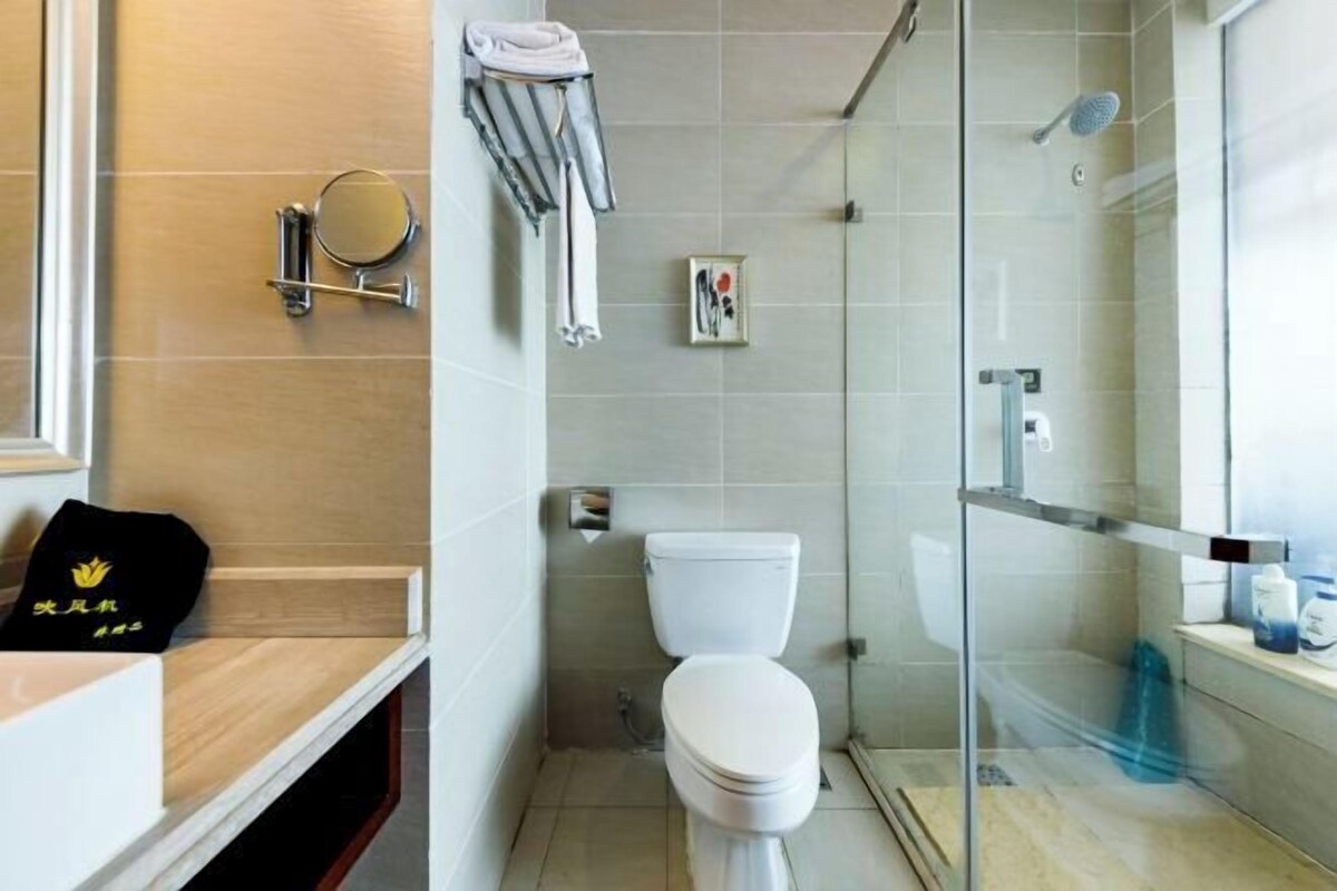 Een moderne badkamer met toilet, douche en een douchecabine met glazen wanden.