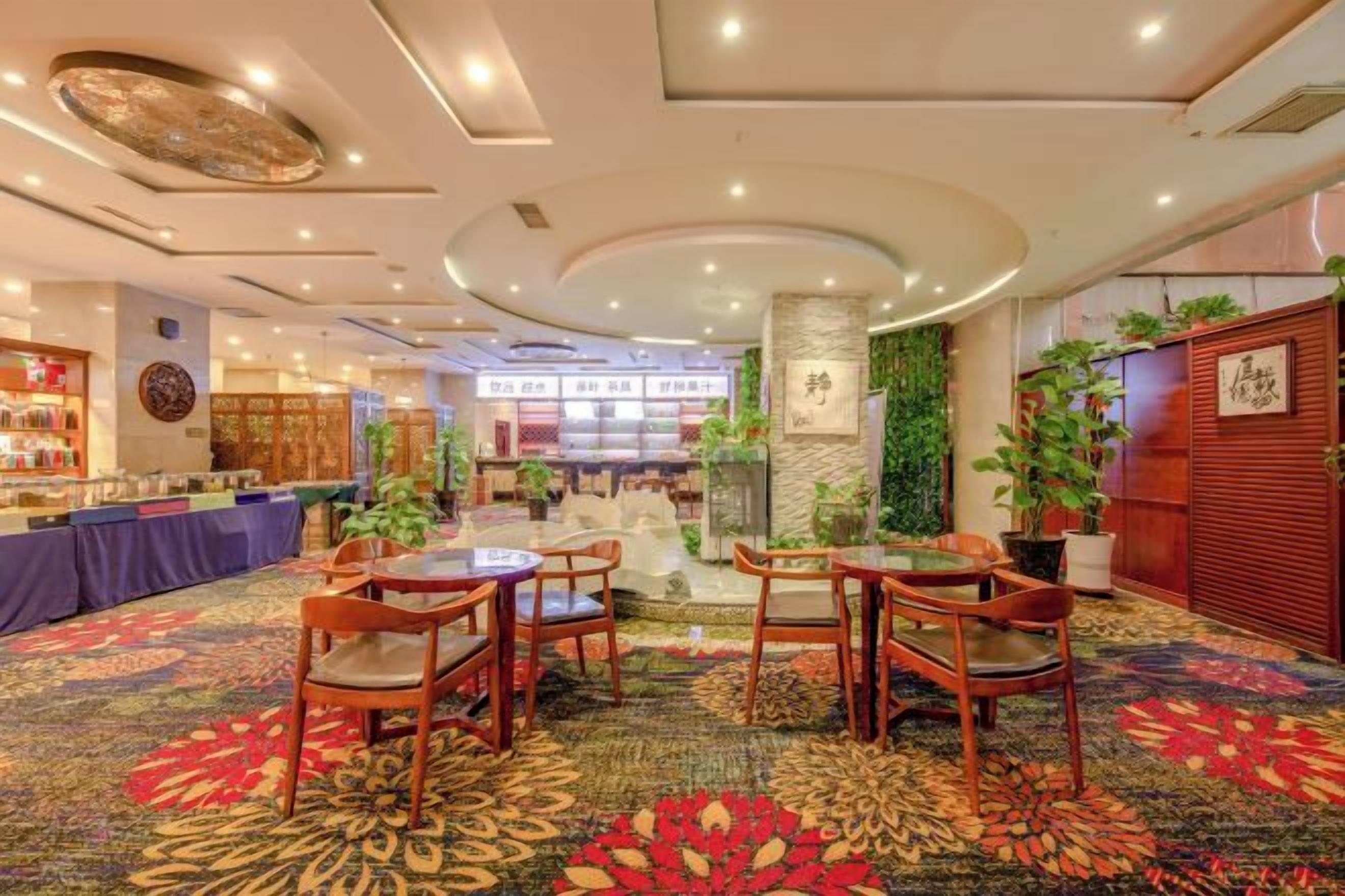 A hotel lobby with a central seating area, a bar, and a reception desk.