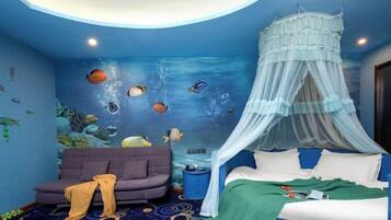 A bedroom with a bed under a canopy, a sofa, and a wall mural of an underwater scene.