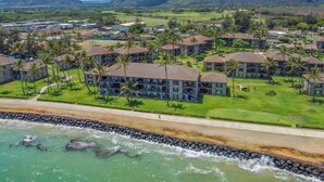 Un resort con varias edificaciones, una playa y montañas al fondo.