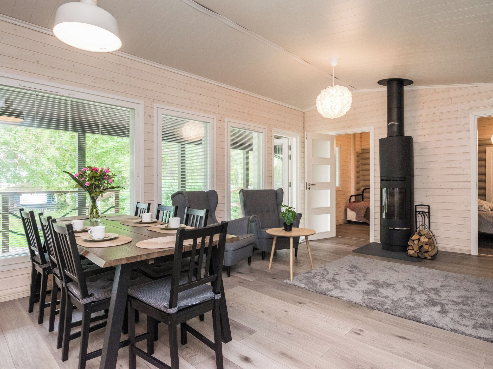 A modern interior with a dining area, seating, a fireplace, and large windows.