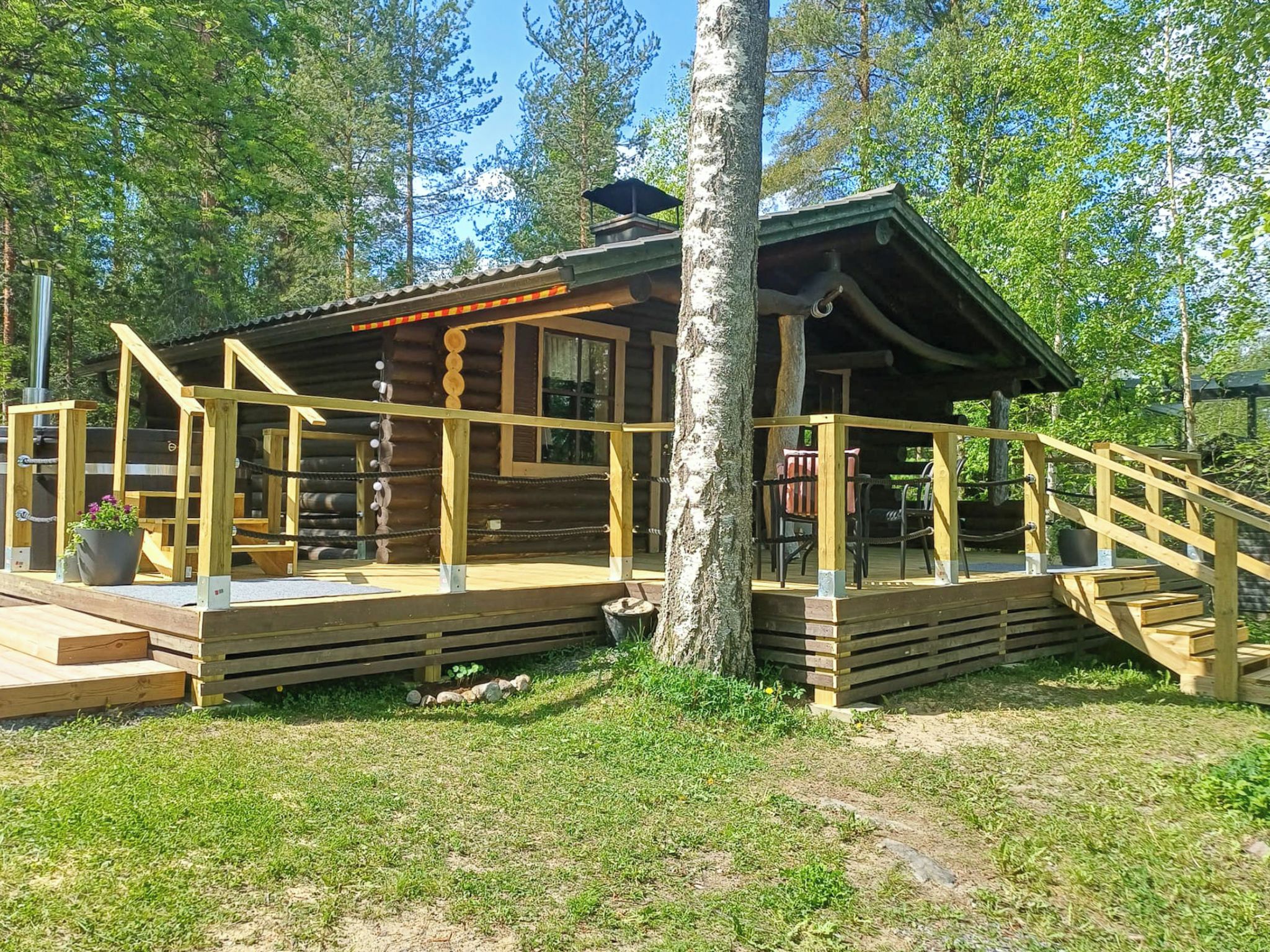 Een houten chalet met een veranda en een trap die er naartoe leidt, omringd door bomen.