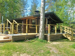 Eine Holzhütte mit einer Veranda und einer Treppe, die zu ihr hinaufführt, umgeben von Bäumen.