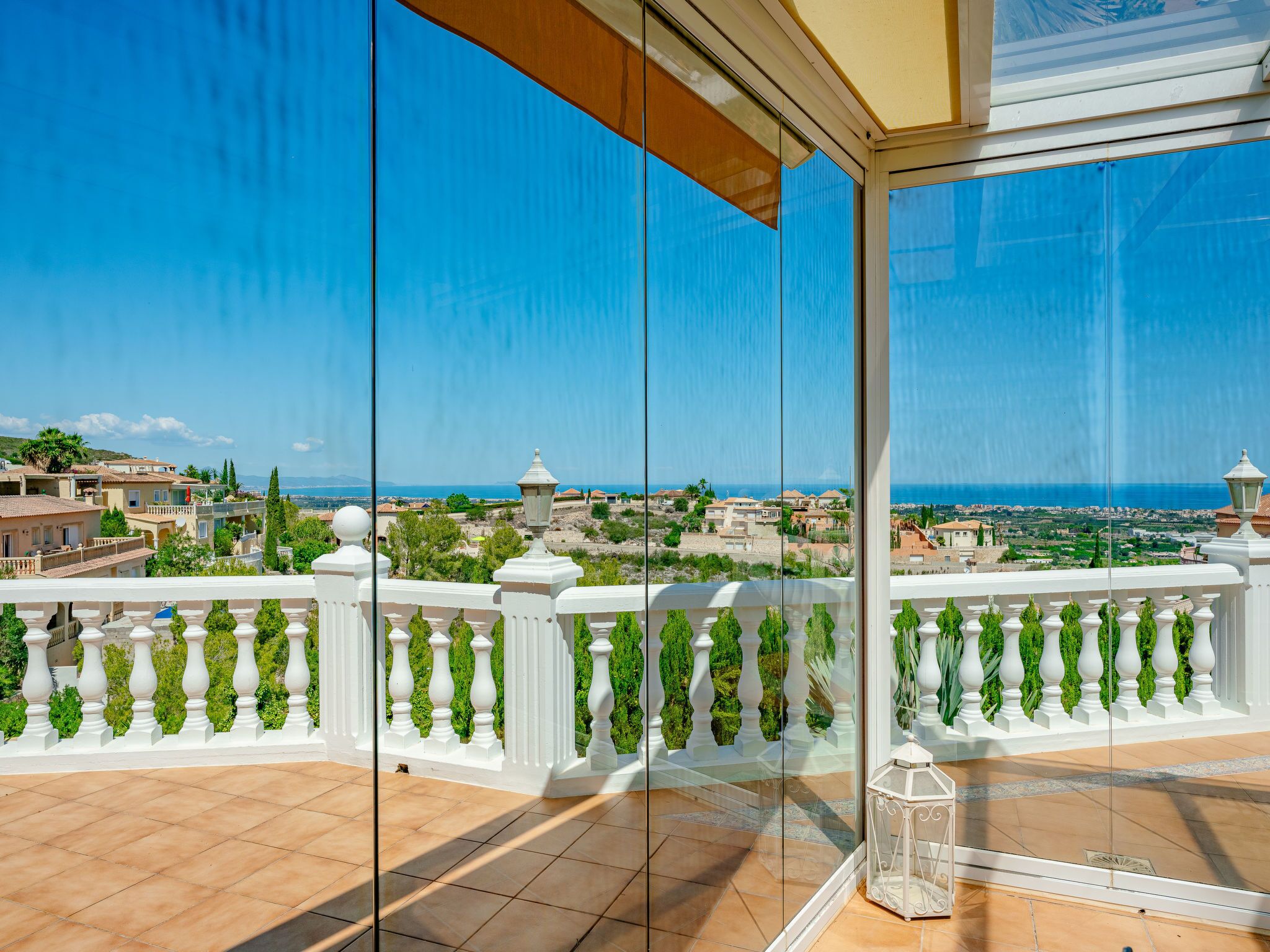 Varanda com vista ampla para uma vila costeira e o mar.