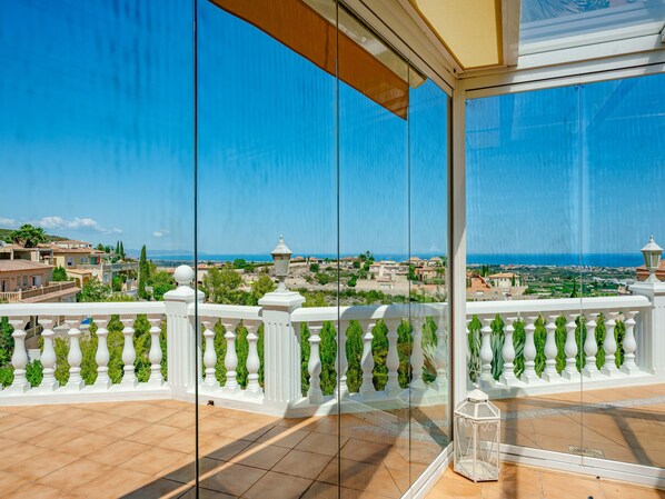 A balcony with a clear view of a coastal town and the sea.