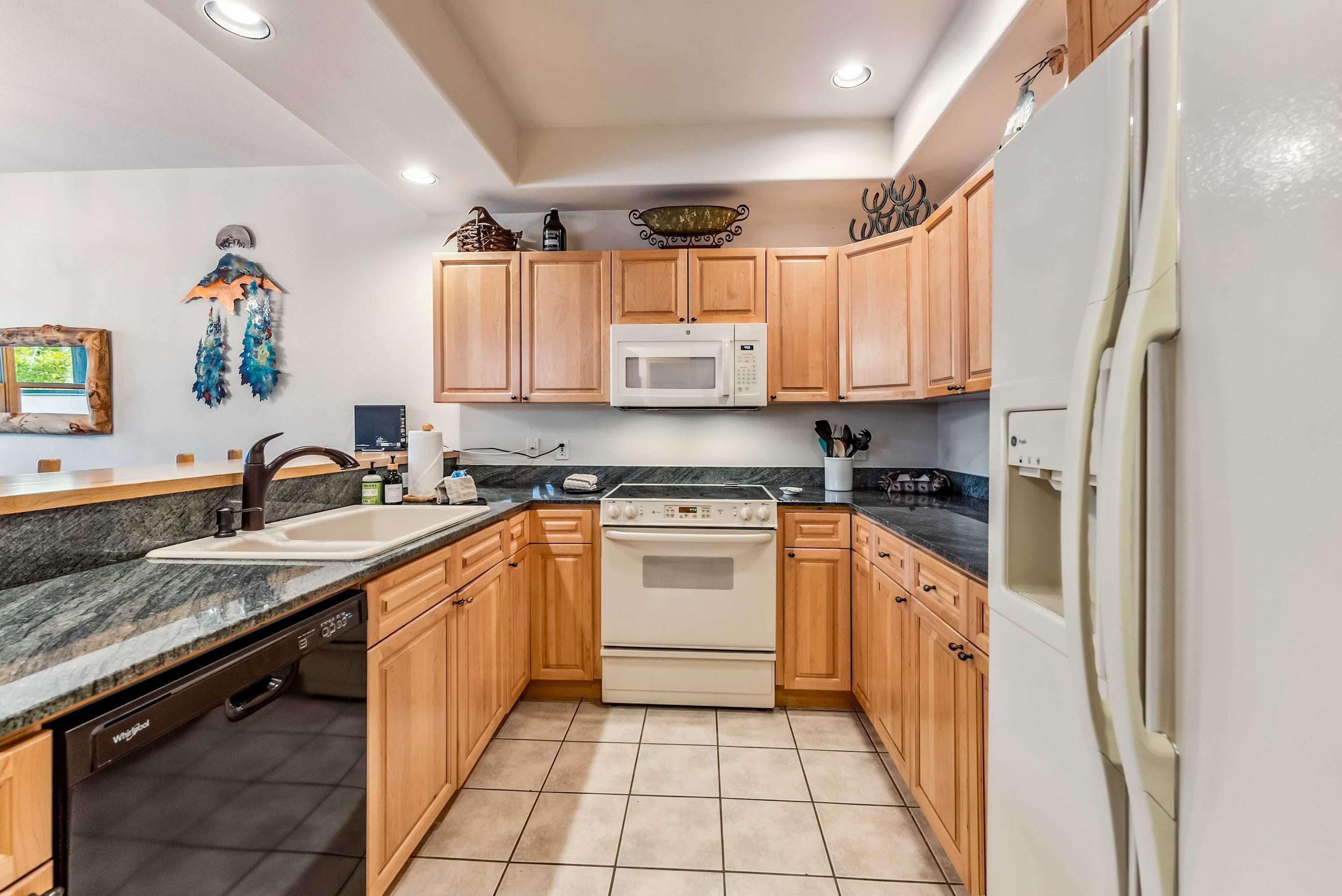 A kitchen with wooden cabinets, a microwave, an oven, a dishwasher, and a refrigerator.