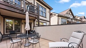 A patio with a round table and chairs, a lounge chair, and a balcony with a railing. - Breckenridge Condo with Hot Tub Access (Breckenridge)