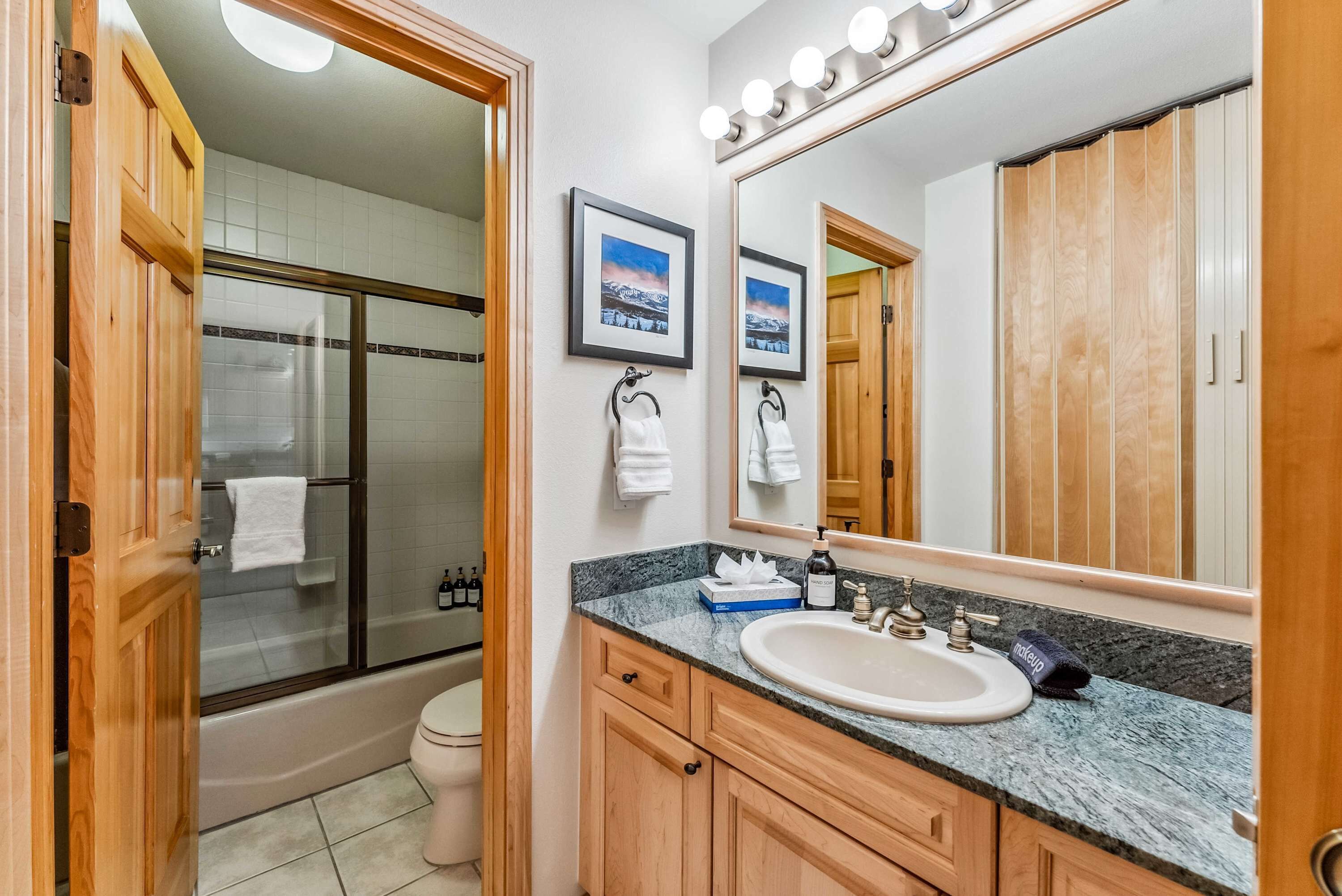 Une salle de bain avec un grand miroir, un lavabo et un espace douche.