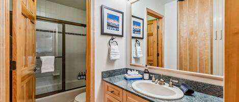 Une salle de bain avec un grand miroir, un lavabo et un espace douche.