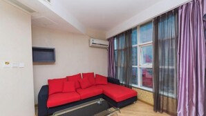 A modern living room with a red sectional sofa, a glass coffee table, and a large window with purple curtains. - Fuerte Hotel Leqing Haian (Yueqing)