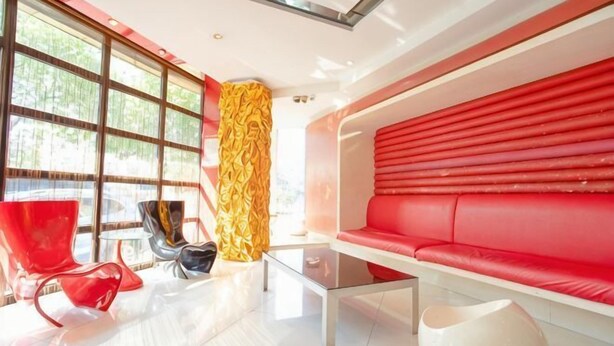 A modern interior with a red sofa, glass coffee table, and red chairs. - Fuerte Hotel Leqing Haian (Yueqing)
