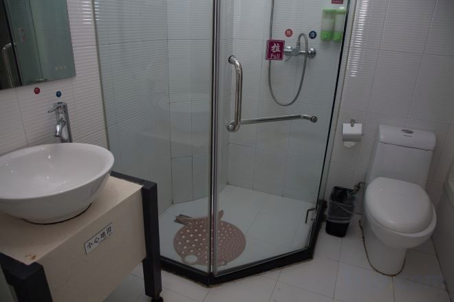 A bathroom with a glass-enclosed shower, a toilet, and a sink.