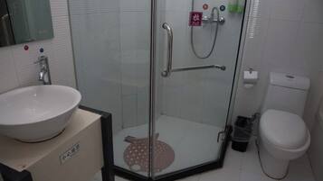 A bathroom with a glass-enclosed shower, a toilet, and a sink.