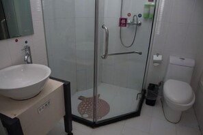 A bathroom with a glass-enclosed shower, a toilet, and a sink.