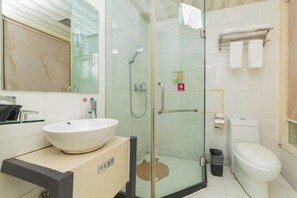 Une salle de bain avec une douche à parois de verre, un lavabo blanc, des toilettes et un porte-serviettes.