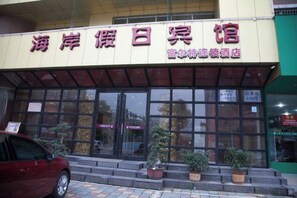 A hotel with a signboard displaying its name and a few windows. There are potted plants on the steps leading to the entrance. - Fuerte Hotel Leqing Haian (Yueqing)