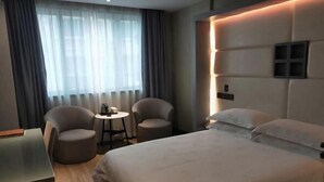A hotel room with a bed, two armchairs, a small table, and a window with curtains. - Fuerte Hotel Leqing Haian (Yueqing)