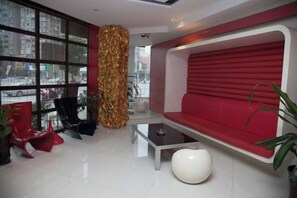A modern interior with a red sofa, black chairs, a glass coffee table, and a large window.