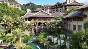 Un resort con arquitectura tradicional, una piscina central y abundante vegetación.