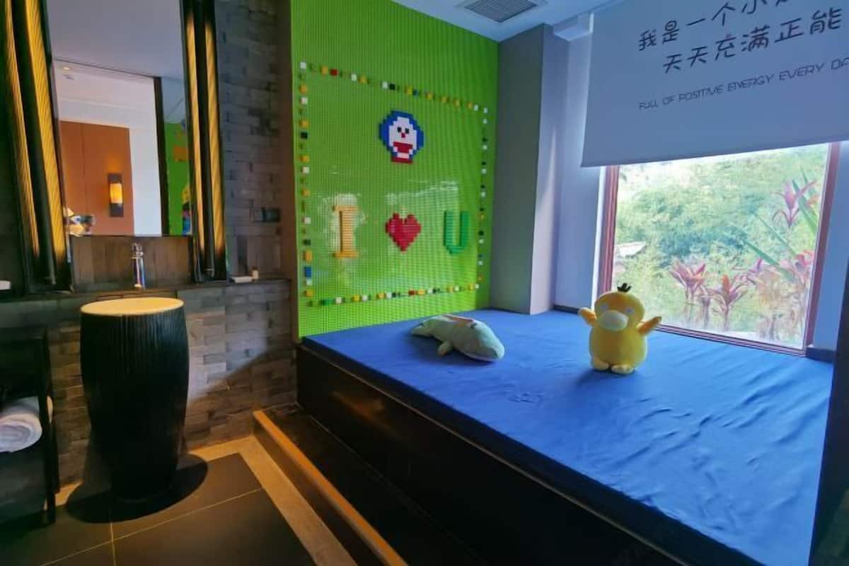 A room with a green wall decorated with colorful letters and a plush toy on a blue bed.