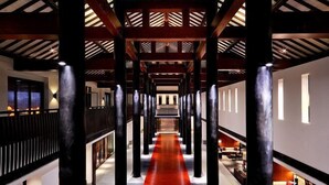 Un pasillo con alfombra roja, vigas de madera y columnas.