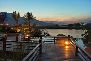A wooden deck with a railing, overlooking a calm body of water and distant mountains. - Fuzhou Guian Xishan Hot Spring Resort (Lianjiang)