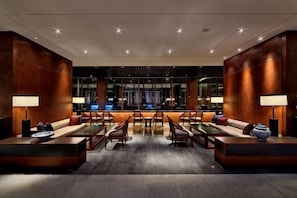 A modern lobby with a reception desk, seating area, and a view of the cityscape.