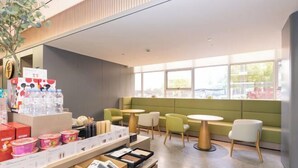 A modern cafe with seating areas, a display of food items, and large windows providing natural light. - JI Hotel (Hangzhou Binjiang University of Chinese Medicine Subway Station) (Hangzhou)