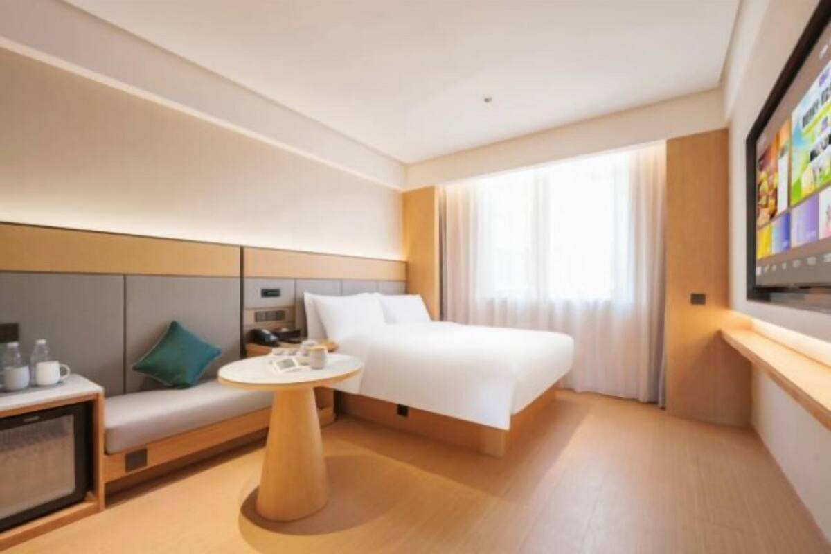Une chambre d’hôtel moderne équipée d’un lit, d’un coin salon, d’une petite table et d’un téléviseur.