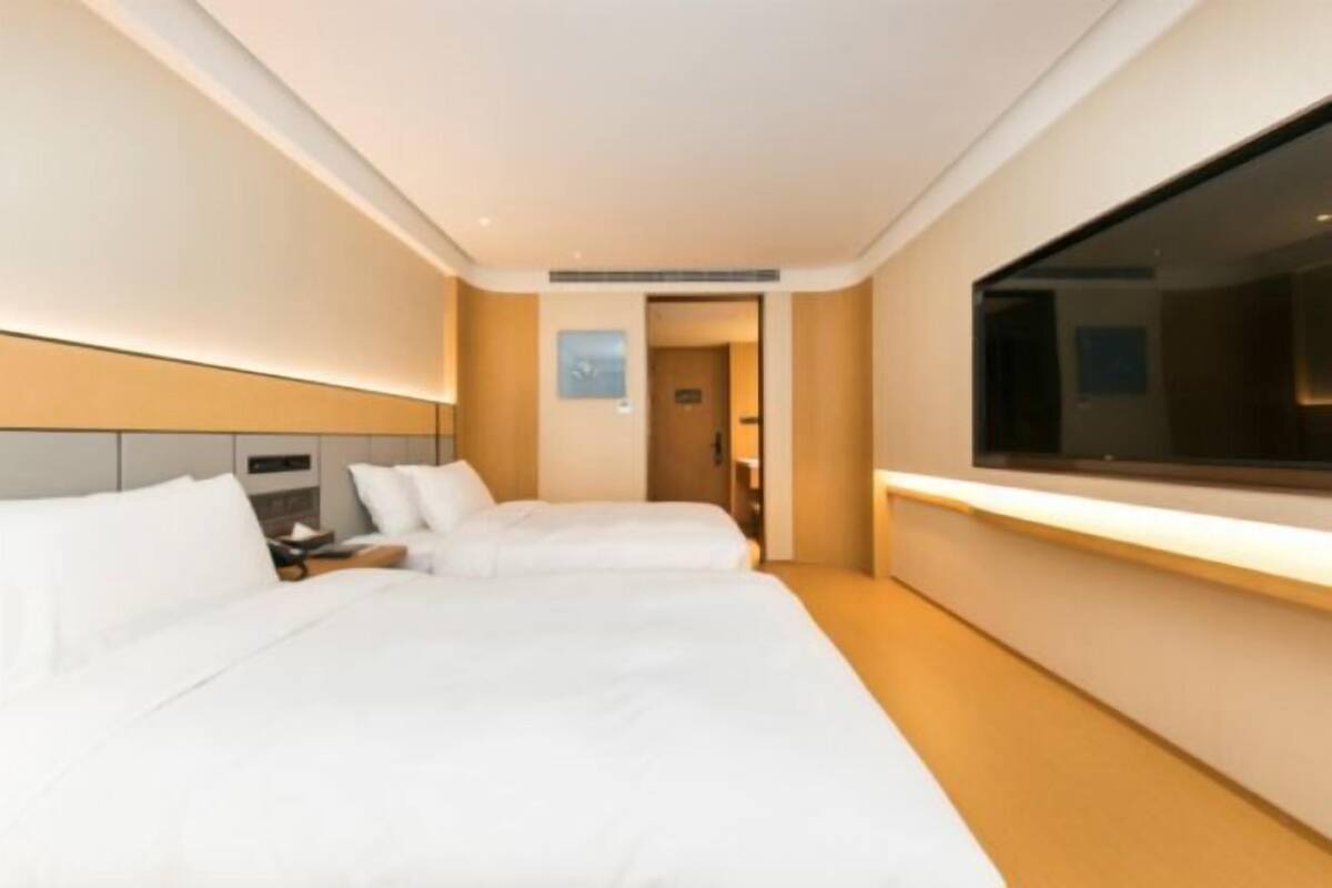 Une chambre d’hôtel avec deux lits, une table de chevet et une grande fenêtre.