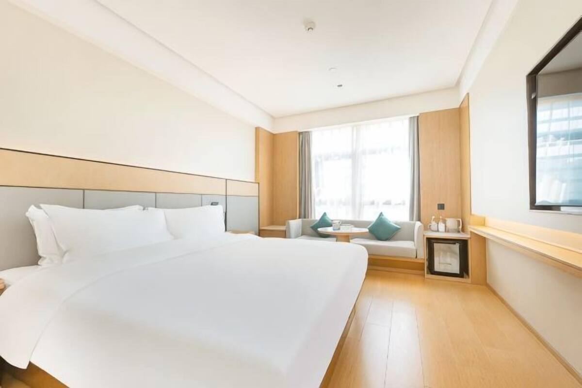 Une chambre d’hôtel avec un grand lit, une table de chevet, une fenêtre et une vue sur l’extérieur.