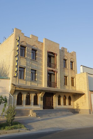 A multi-story building with a prominent arched entrance and a balcony on the second floor. - Hotel Xansaroy (Samarkand)
