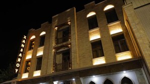 A building with a prominent sign reading "XANSAROY" at night, featuring a symmetrical facade with multiple windows and a central entrance. - Hotel Xansaroy (Samarkand)