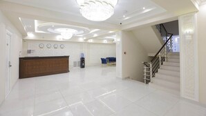 A spacious lobby with a reception desk, a chandelier, a staircase, and a water dispenser. - Hotel Xansaroy (Samarkand)