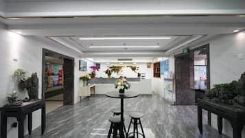 A hotel lobby with a reception desk, a round table with stools, and a marble floor.