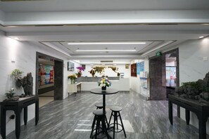 A hotel lobby with a reception desk, a round table with stools, and a marble floor. - Zhongyouyuan Hotel (Beijing Niujie Metro Station Xuanwu Hospital Branch (Beijing)