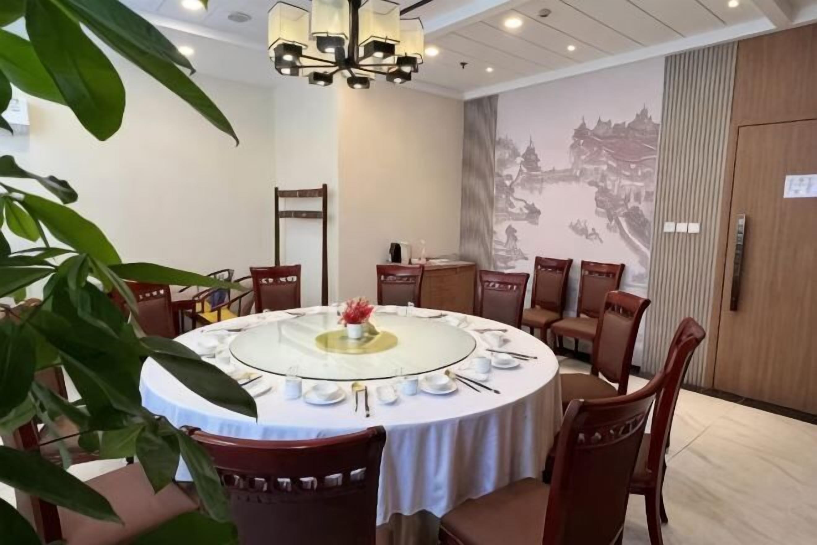 A round dining table with chairs, a chandelier, and a mural on the wall.