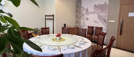 A round dining table with chairs, a chandelier, and a mural on the wall.