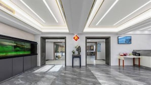 En rymlig entréhall med ett stort akvarium, en receptionsdisk och en modern takdesign.